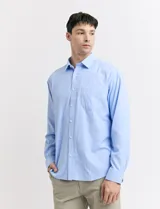 Camisa celeste de vestir, de manga larga, con cuello clásico y bolsillo en el pecho.