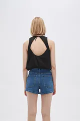 Blusa blanca de algodón sin mangas, con cuello a la base, abertura en la espalda y lazo ajustable.