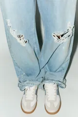 Zapatillas deportivas blancas con detalles en celeste y suela color caramelo.