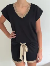 Conjunto de pijama de dos piezas color negro, compuesto por una remera de manga corta con escote en V adornado con puntilla beige, y un short con lazo frontal beige y terminación de puntilla beige en el ruedo.
