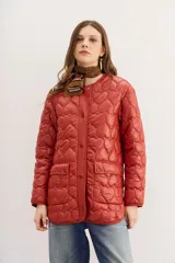 Campera color ladrillo con matelassé de corazones, corte amplio, mangas largas y bolsillos con solapa y botones snap en el frente.
