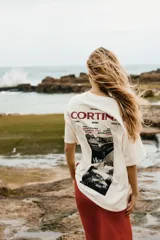 Remera blanca de algodón con corte oversized, cuello redondo y estampado frontal con texto en color rojo.