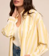 Camisa de viscolino con estampado de rayas verticales amarillas y blancas, corte alargado, cuello inglés, mangas largas y bolsillo en el pecho.
