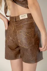 Short negro de cuero sintético, corte jean, con bolsillos delanteros y traseros.