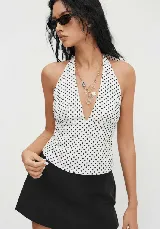 Top halter blanco con lunares negros, escote en V y tiras para atar en la nuca.