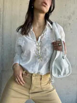 Camisa blanca de manga larga con bordado floral.