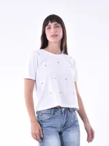 Remera blanca de algodón, corte cropped y manga corta, con pequeños bordados de cerezas rojas distribuidos por toda la prenda.