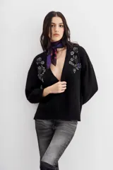 Cardigan negro de tejido de punto con ochos y terminaciones en punto rib. Presenta calce relajado, mangas largas y apliques bordados en piedras y canutillos en la parte superior del frente.