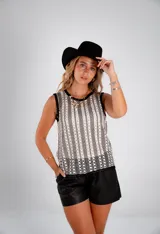Blusa sin mangas de crochet calado en blanco y negro, con cuello redondo y ribete negro en sisas y cuello.