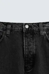 Pantalón de jean negro de corte amplio, estilo balloon fit, con cinco bolsillos y cierre frontal con botones.