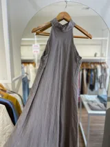 Vestido largo confeccionado en 100% lino, con cuello halter y silueta fluida en color beige.