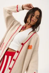 Saco oversize tejido con ilustraciones inspiradas en corales, peces, estrellas de mar y tortugas. Presenta galón picot en rojo en cartera y puños, y botones a tono.