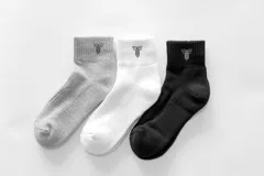 Pack de tres pares de medias de caña media, color negro, blanco y gris, con logo en el tobillo.