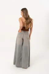 Jean súper campana de tiro alto, color celeste vintage, con pierna extra ancha y caída fluida. Cuenta con bolsillos delanteros y traseros, y cierre frontal con cremallera y botón metálico.