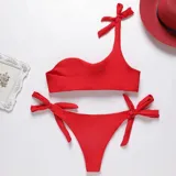 Conjunto de bikini rojo con corpiño de un solo hombro con lazo y bombacha con lazos laterales.