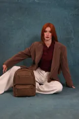 Mochila color marrón de símil cuero con un compartimento principal amplio, bolsillo al frente con cierre, correas ajustables y asa.