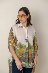 Camisa italiana de corte irregular, estampada con diseño de ananás y otros motivos en tonos verde, marrón y amarillo, sobre fondo natural.