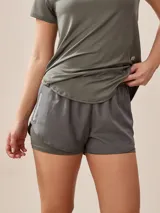 Short deportivo verde militar con calza interna, cintura elástica y logo estampado en la pierna.