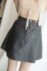 Minifalda negra de cuero con corte en A y costuras verticales decorativas.