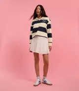 Suéter slim con cuello polo, manga larga y rayas horizontales en tonos crema y azul marino. Presenta lettering "NYC" bordado en el pecho y está confeccionado en algodón con forro fleece.