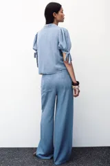 Pantalón celeste de tiro alto con cintura elástica ajustable con cordones, bolsillos delanteros y traseros, y pernera ancha.