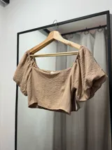 Top corto color marrón claro, con escote cuadrado, mangas cortas abullonadas con elástico y espalda fruncida.