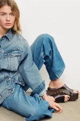 Mules de cuero marrón con plataforma de madera y detalle de tachas doradas.