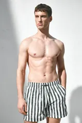 Short de baño blanco con rayas verticales verdes, cintura elástica con cordón ajustable, bolsillos laterales y bolsillo trasero con cierre autoadherente.