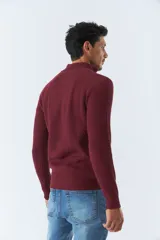 Sweater borgoña de punto acanalado, con cuello alto y medio cierre frontal.