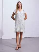 Vestido corto estampado, marca Marissa Olivia. Cuello a la base con frunce y lazo de ajuste. Terminación de ruedo con volado. Forro interno a tono.