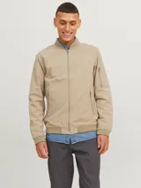 Campera bomber color beige con cuello de béisbol, cierre con cremallera, bolsillos frontales con cremallera y bolsillo en la manga.