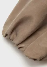 Mono largo color beige, con corte palazzo, escote asimétrico de un hombro, manga corta abullonada y cintura elastizada.