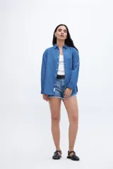 Camisa de denim azul de algodón, con cuello solapa, calce relaxed, manga larga y bolsillo cuadrado en el pecho. Cierre frontal con botones personalizados.