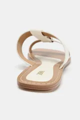 Sandalia plana color crema con doble tira y hebilla metálica dorada.