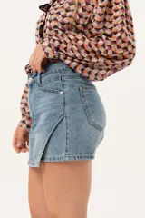 Minifalda de jean azul claro con corte evasé, detalle de short interno y cinturón negro con argollas metálicas.