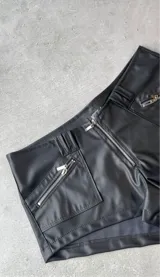 Short negro de cuero sintético con bolsillos frontales con cierre.