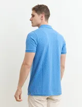 Chomba celeste con estampado de lunares blancos, cuello clásico y mangas cortas.