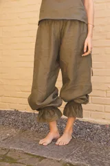Pantalón de lino color verde oliva, de corte amplio con frunces elásticos en el ruedo.