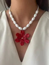 Collar de cuentas blancas con dije de flor roja de metal con centro de perla.