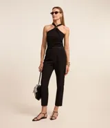 Pantalón de vestir negro, de corte zanahoria, con cinturón fino con hebilla metálica.
