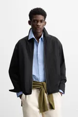 Sobrecamisa color crema de tejido técnico ligero, corte regular fit, cuello solapa, manga larga con puños abotonados, bajo ajustable con elástico en laterales y cierre frontal con cremallera.