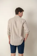 Camisa celeste de lino con cuello clásico y manga larga. Presenta un pequeño logo bordado en el pecho.