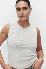 Musculosa de punto color gris claro, con cuello redondo y sin mangas. Decorada con strass plateado de diferentes tamaños.