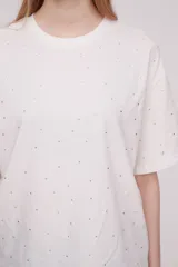 Remera blanca de algodón con pequeños apliques brillantes.