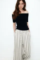 Pantalón de corte holgado en tejido liviano de mezcla de lino. Modelo de tiro alto con cintura elástica y cordón para ajustar fino, bolsillos laterales discretos y piernas rectas. Diseño a rayas verticales en blanco y negro.