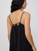 Vestido corto de algodón y lino color negro, con tirantes finos y escote recto con lazo ajustable.