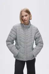 Campera puffer estampada a cuadros en blanco y negro con pequeños corazones rosados, cierre frontal con cremallera y bolsillos laterales.