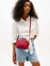 Bandolera Tommy Jeans roja con acabado granulado, cierre de cremallera, correa ajustable y logo tonal en el frente.