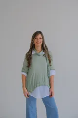 Sweater verde con cuello alto, mangas 3/4 y bajo asimétrico. Incluye una camisa blanca de mangas largas y una bufanda de encaje verde.