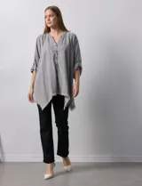 Camisa celeste de tencel, corte amplio, con cuello mao, escote en V y abotonadura frontal. Tiene bolsillos aplicados en el pecho, mangas 3/4 regulables con presilla y ruedo desflecado.